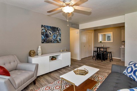 A living room with a grey couch, a white coffee table, and a ceiling fan. at Reflections at Red Mountain Apartments, Mesa 85213