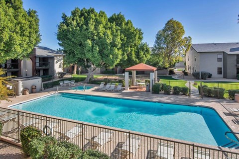 A swimming pool surrounded by a fence and trees at Reflections at Red Mountain Apartments, Mesa, Arizona