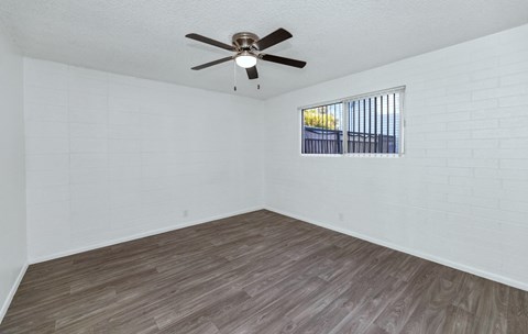 A room with a ceiling fan and a window with bars at The Phoenix Apartments on 6th Avenue, Phoenix, Arizona