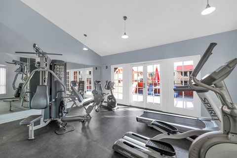 A gym with a variety of equipment including treadmills, stationary bikes, and weight machines at Urban WalkApartments on 6th Avenue, Phoenix 85016