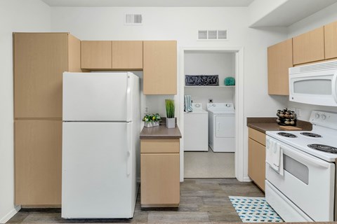 A white refrigerator is in a kitchen with tan cabinets.