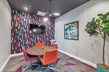 a conference room with a table and chairs and a television