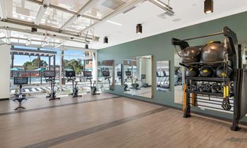 a gym with a large window and a large amount of exercise equipment at Melody on Main, Mesa, 85210