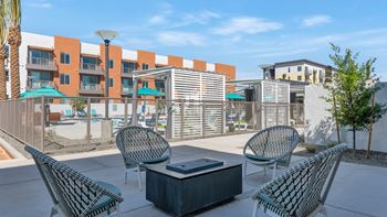 a patio with chairs and tables and a building in the background