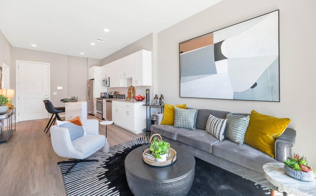 a living room with a couch and a table in front of a kitchen with a stove at Melody on Main, Mesa, 85210