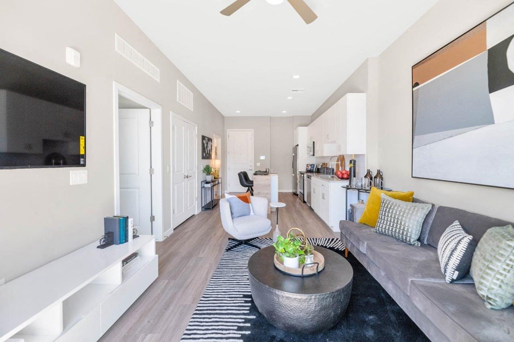 a living room with a couch and a table in front of a tv at Melody on Main, Mesa, AZ