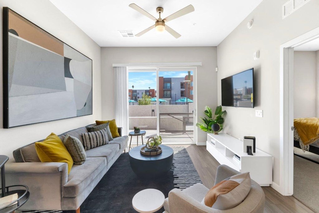 a living room with a couch and a tv in front of a sliding glass door at Melody on Main, Arizona, 85210