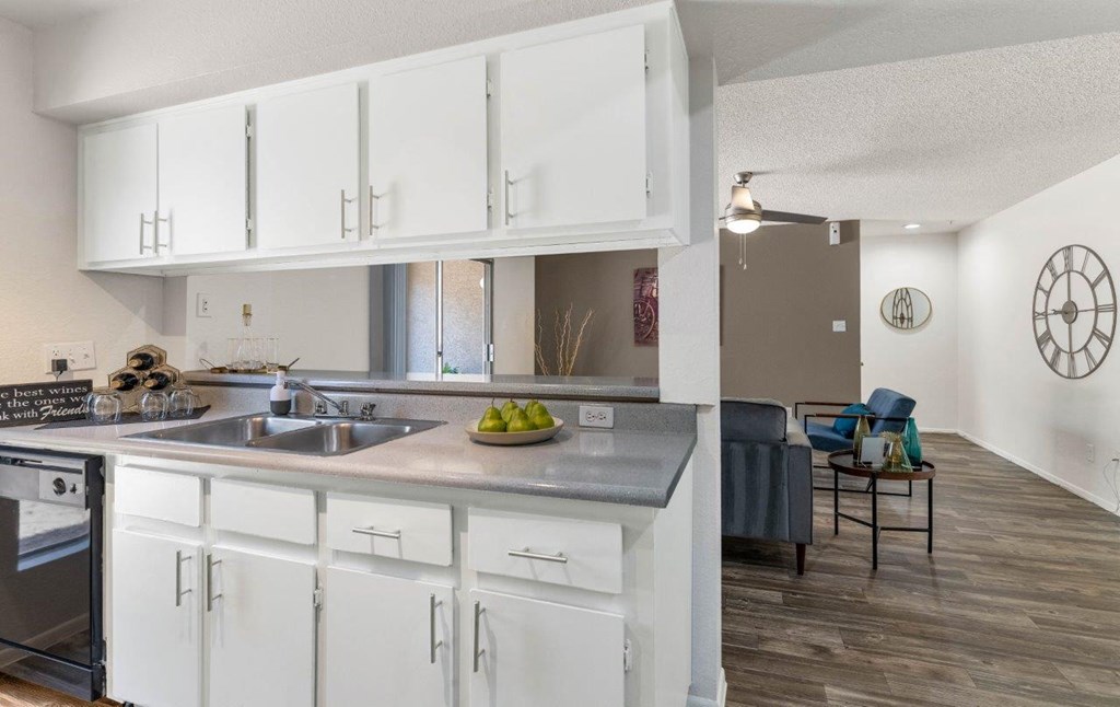a kitchen and living room with white cabinets and a sink  at Glen Brae, Glendale, 85301