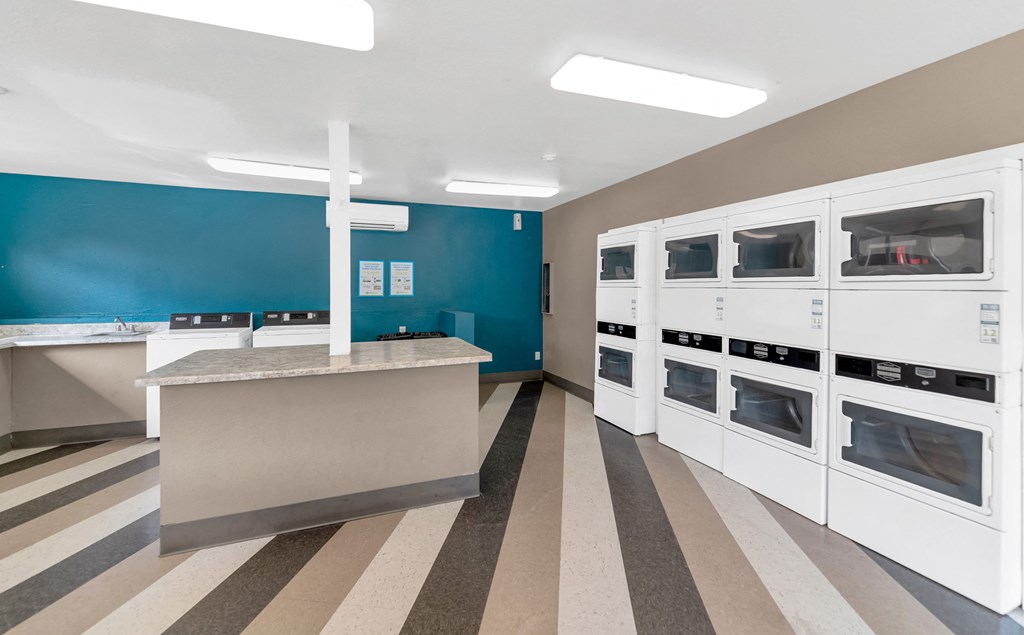 a kitchen with white cabinets and a counter and a blue wall