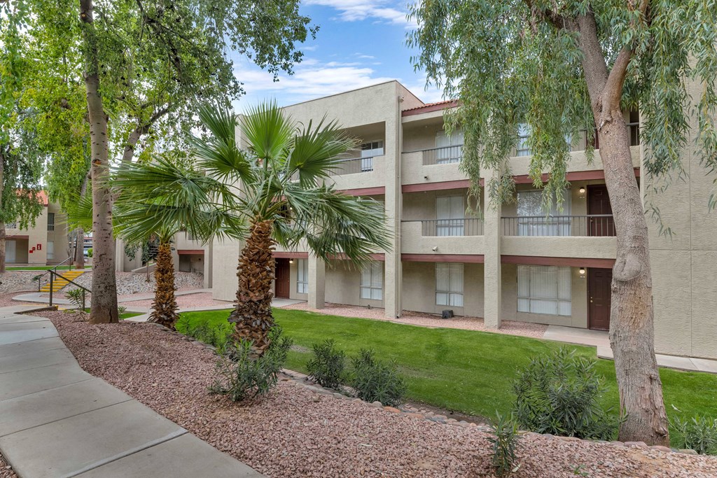 a building with a sidewalk and palm trees in front of it