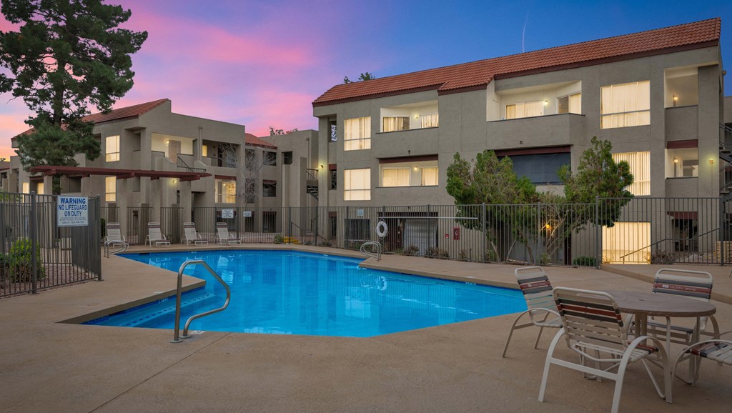a swimming pool at night in front of an apartment building