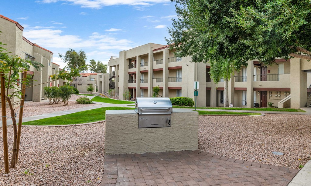 an outdoor area with a grill in front of an apartment building