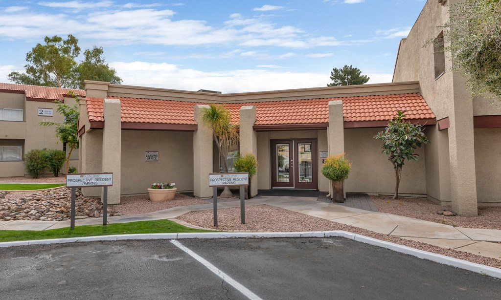 the front of a building with a driveway and a parking lot