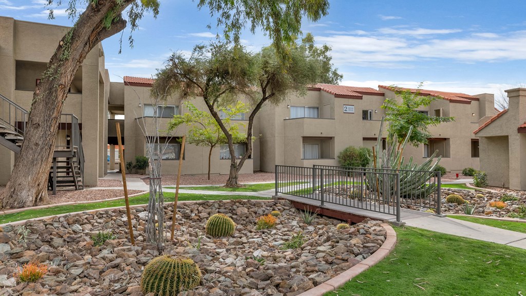 an apartment building with a courtyard with cactus and rocks