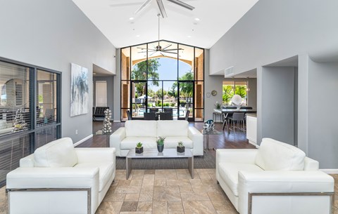 A modern living room with white furniture and a large window.