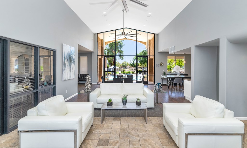 A modern living room with white furniture and a large window.