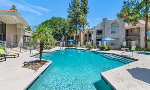 A swimming pool surrounded by a concrete patio and a building in the background.