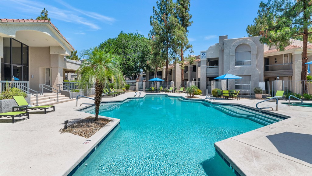 A swimming pool surrounded by a concrete patio and a few trees.