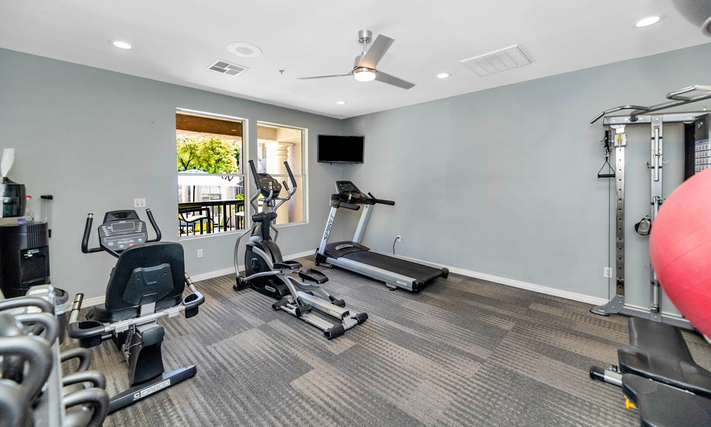 A spacious gym with a variety of equipment including treadmills, elliptical machines, and weight machines.