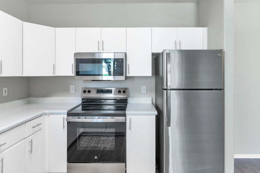 A modern kitchen with a stainless steel refrigerator, oven, and microwave.
