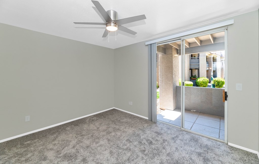 A room with a ceiling fan and carpeted floor.
