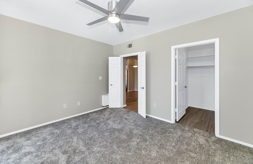 A room with a ceiling fan and two open doors.