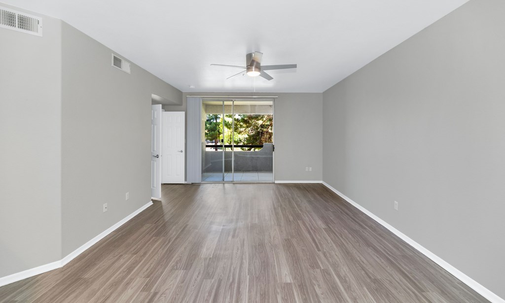 A room with a ceiling fan and a sliding glass door leading to a balcony.