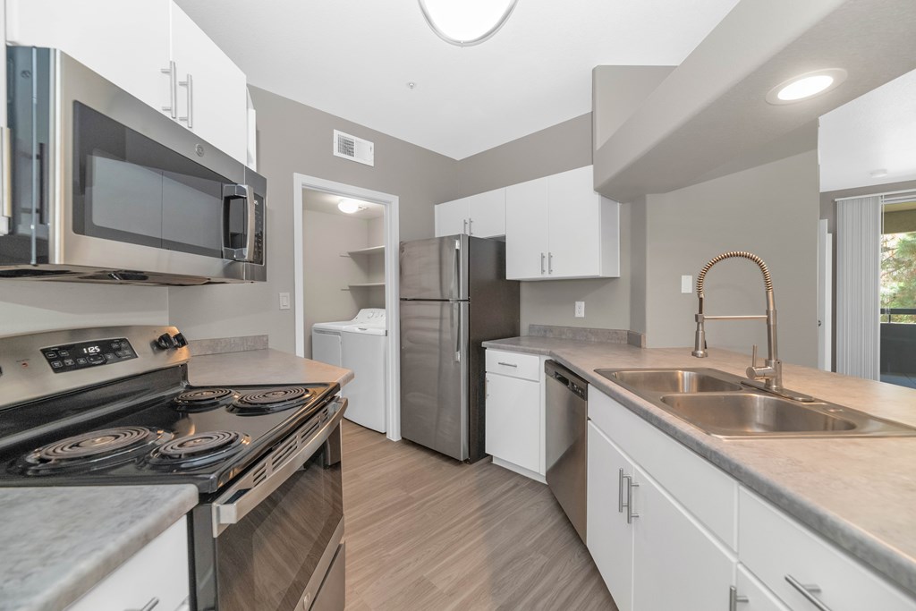 A modern kitchen with a stove top oven, microwave, refrigerator, and dishwasher.