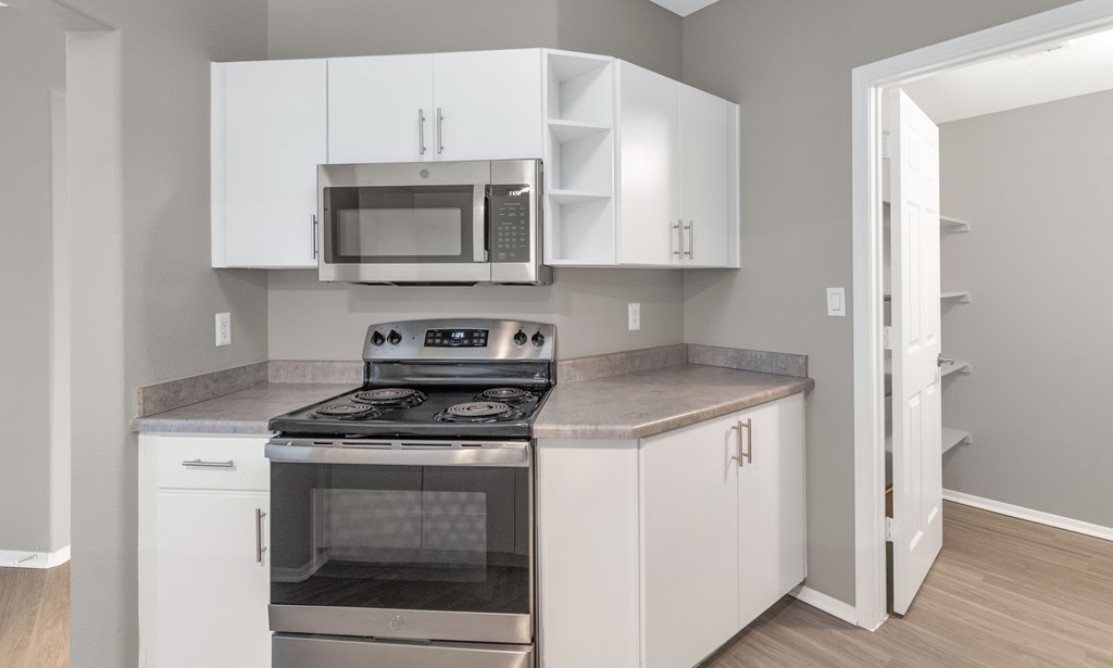 A kitchen with white cabinets and a stainless steel stove top oven.