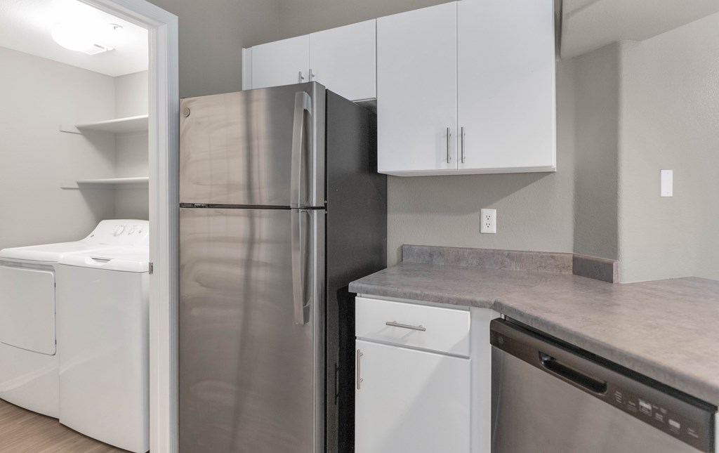 A kitchen with a refrigerator, dishwasher, and oven.