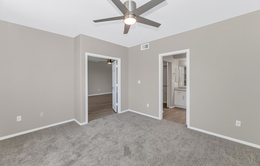 A room with a ceiling fan and two open doors.
