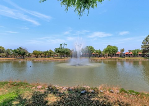 A fountain in the middle of a lake surrounded by trees.