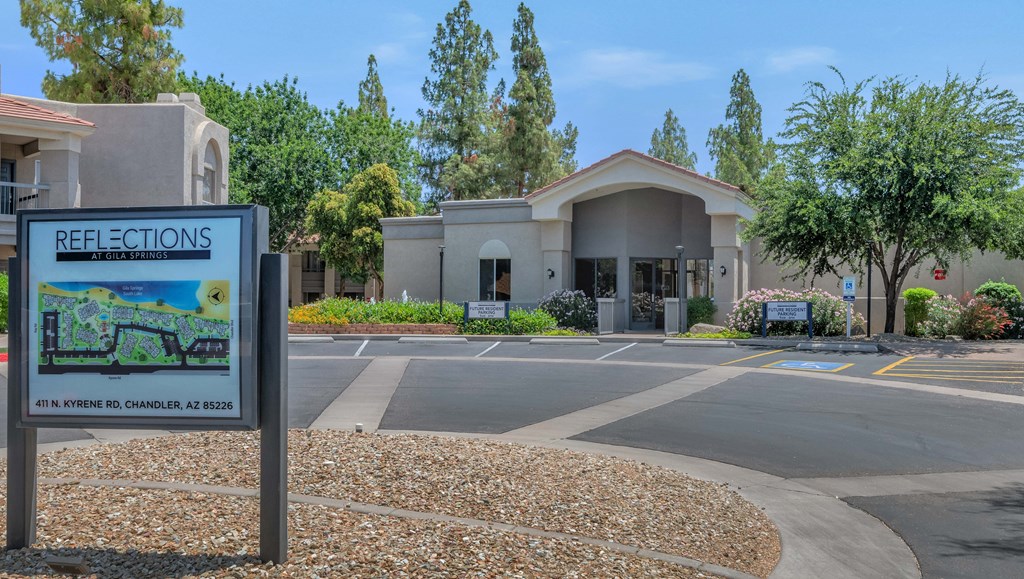 A sign for Reflections at the entrance of a building with a parking lot in front.