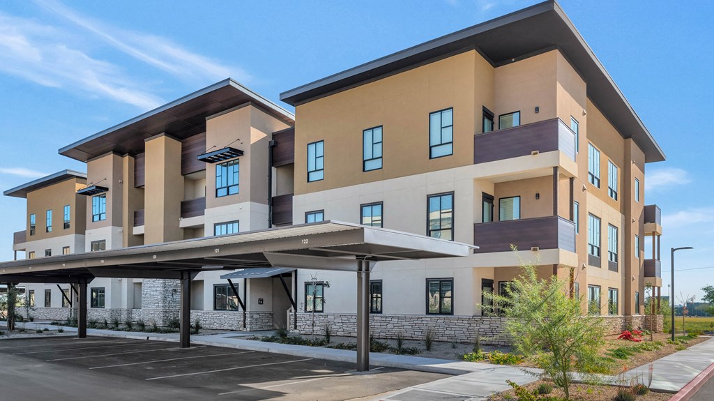 a large apartment building with an awning in front of a parking lot