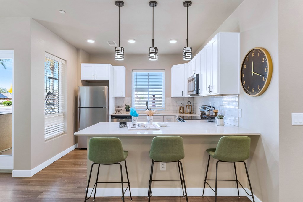 a kitchen with a island with three stools    and a large clock