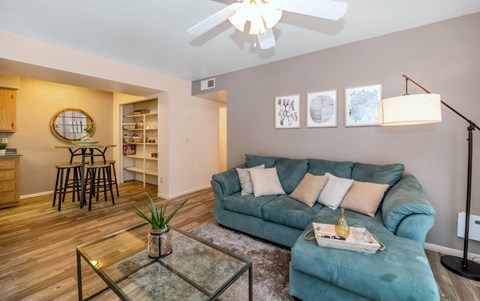 A living room with a blue couch and a glass coffee table.