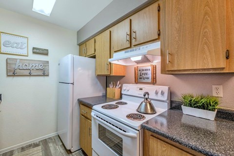 A kitchen with a white stove top oven and white refrigerator.