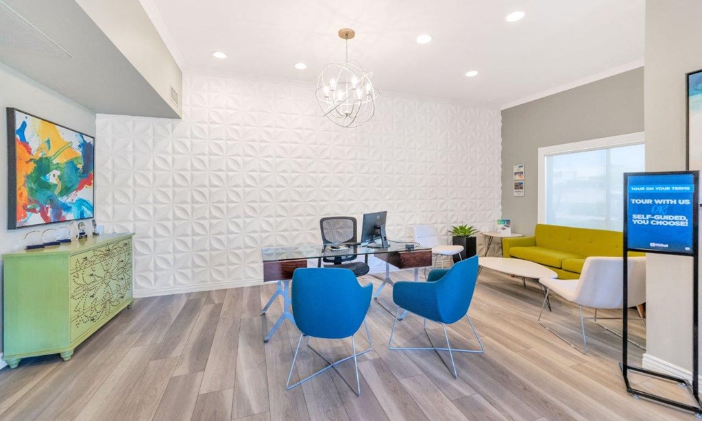 a room with a desk with a computer on it and a yellow couch in the background