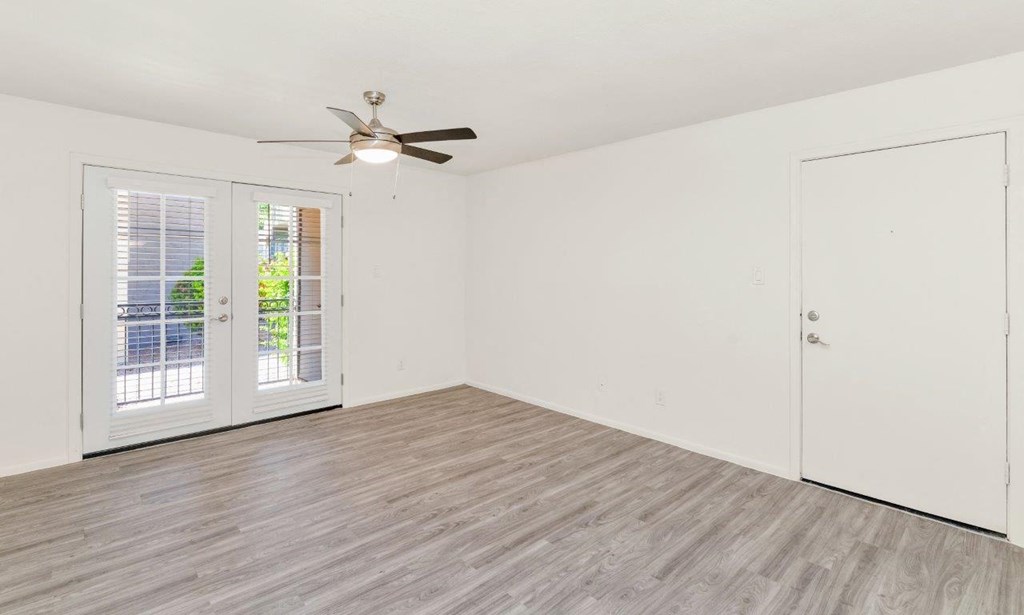 a bedroom with a ceiling fan and a door to a balcony
