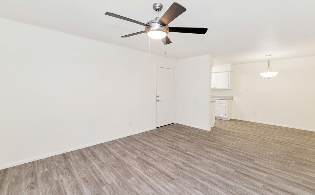 an empty living room with a ceiling fan