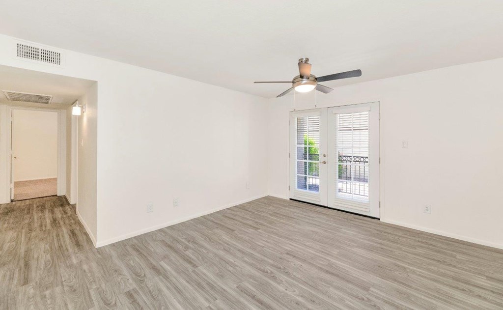 an empty living room with a ceiling fan