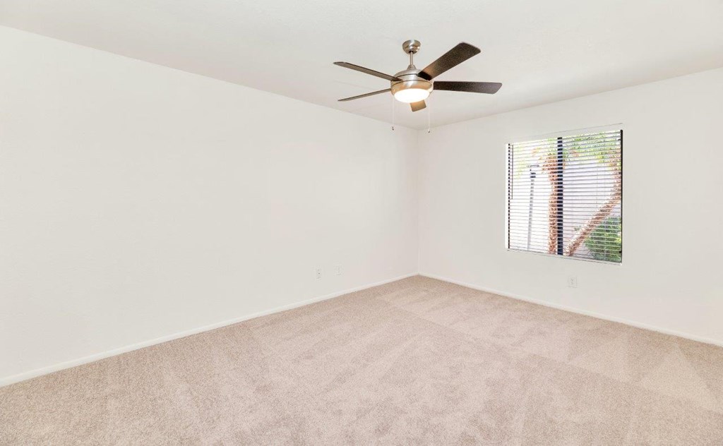a bedroom with white walls and a ceiling fan
