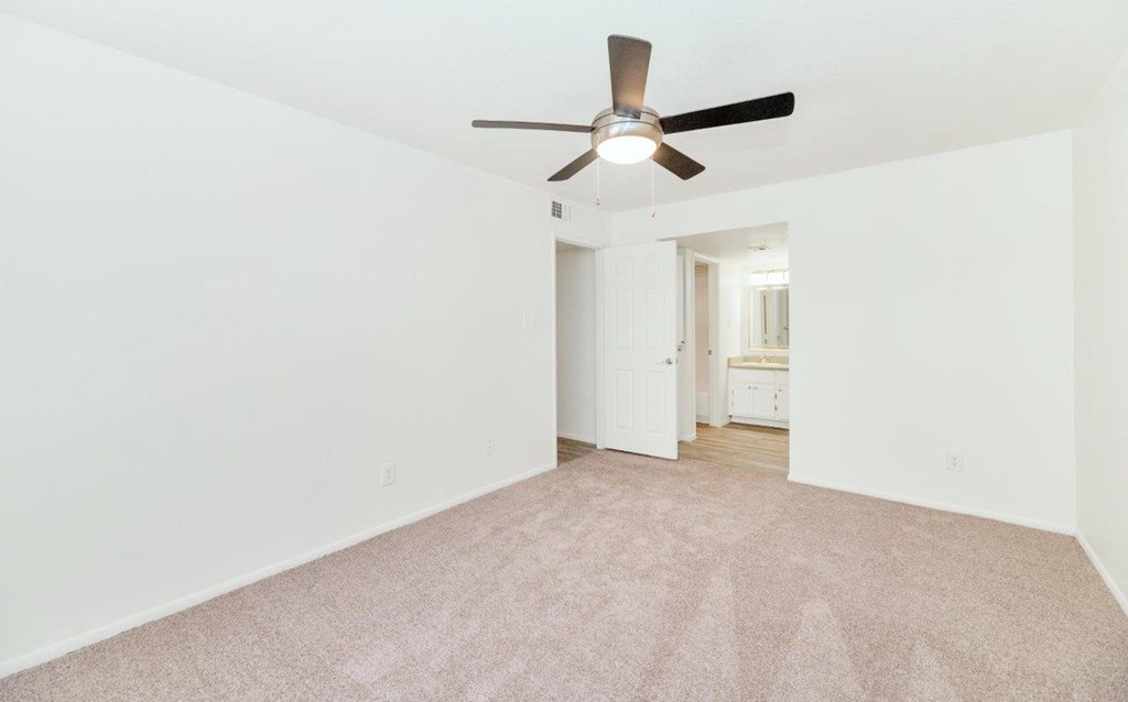 an empty living room with a ceiling fan