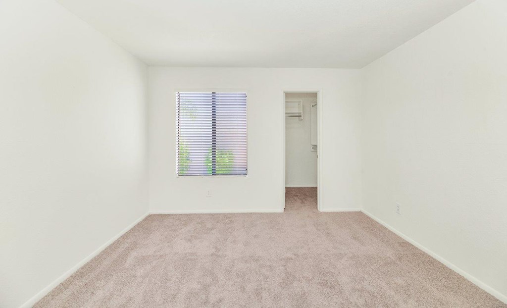 a bedroom with white walls and a window