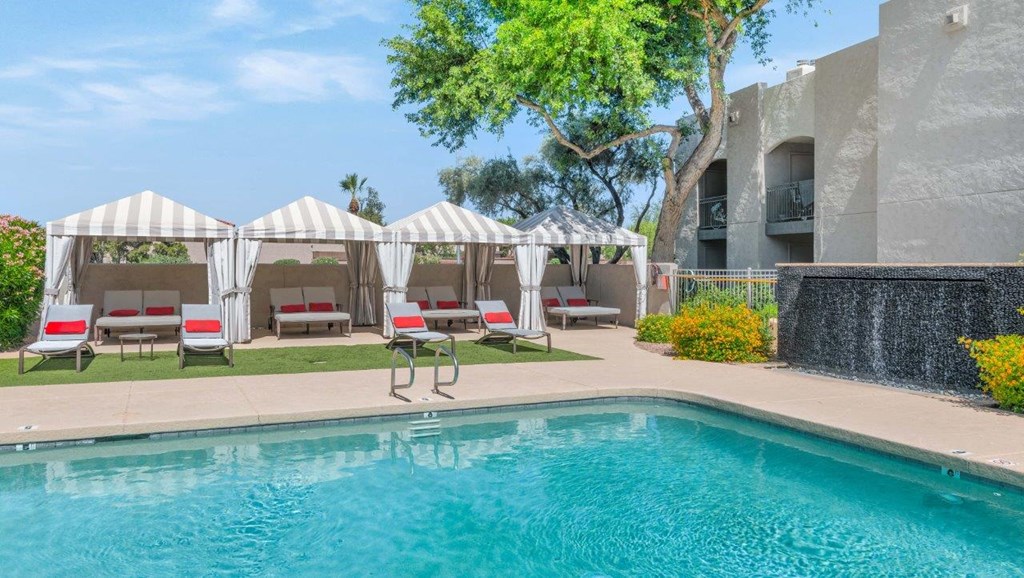 a resort style pool with lounge chairs and umbrellas