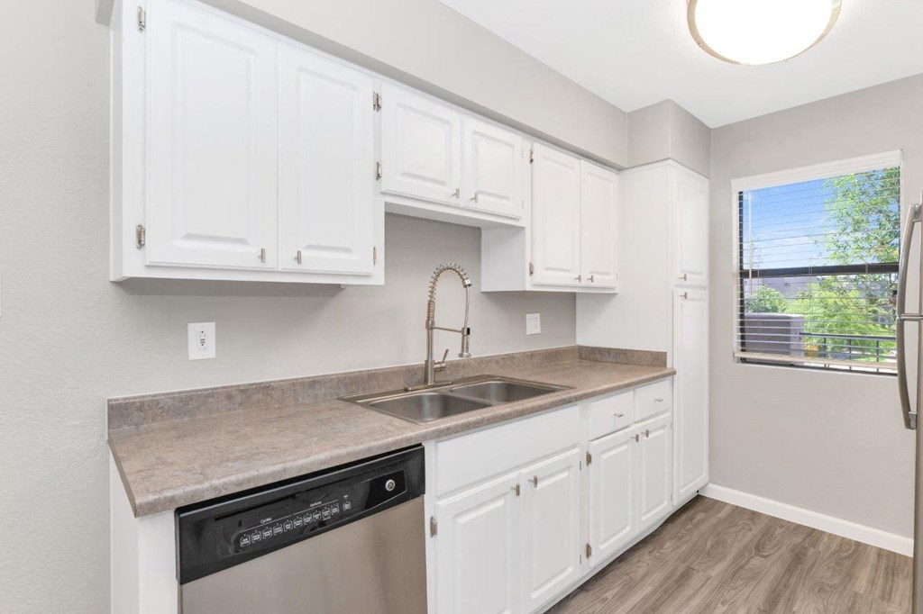 a kitchen with white cabinets and a stainless steel dishwasher