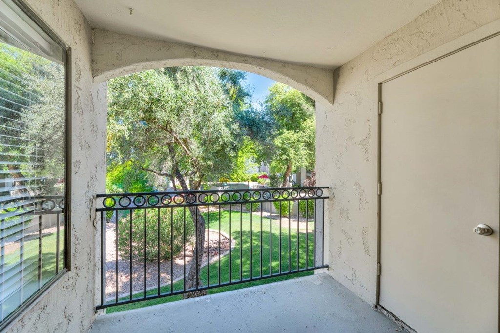 a balcony with a door and a grassy area in the background