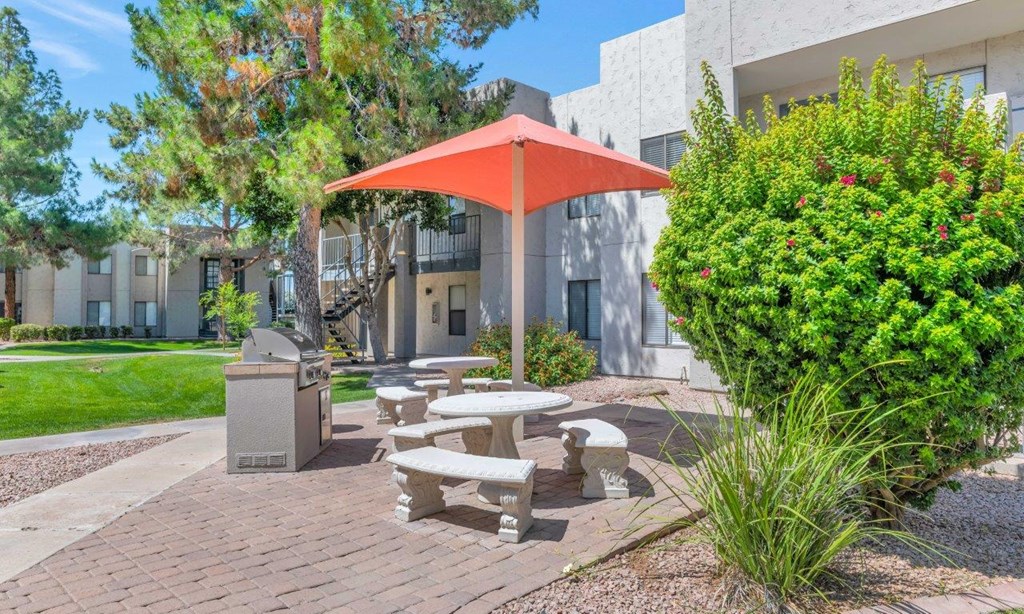 a picnic table with a red umbrella in front of a building