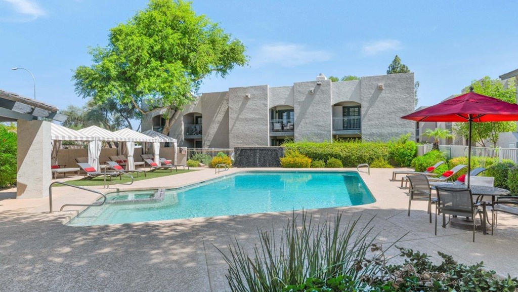 a swimming pool with chairs and umbrellas and a building in the background