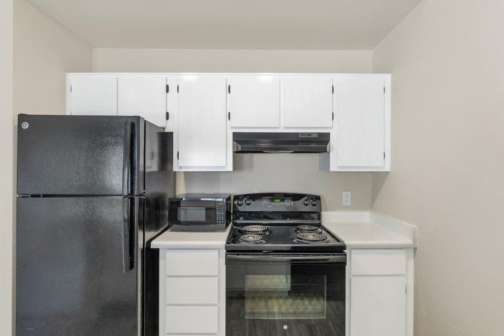 a kitchen with white cabinets and black appliances
